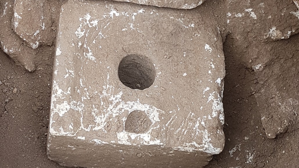 An ancient toilet that looks like a square stone block with a circular hole in the middle