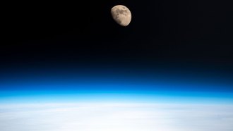 A photo of the moon as seen from Earth's orbit with the a blue haze at the bottom of the image.