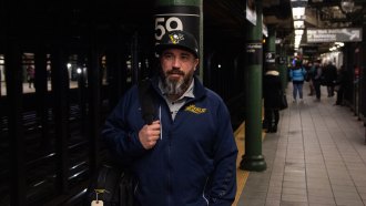 Jon Nelson walks along a New York subway platform holding a bag.