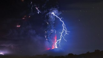 Lightning strikes above an erupting volcano