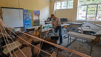 A Kharkiv Polytechnic Institute staff member sifts through the debris of a classroom destroyed by a Russian missile